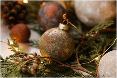 an ornament hanging from a tree with pine cones and other ornaments around it