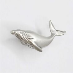 a silver whale brooch sitting on top of a white table