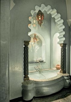 a bathtub in the middle of a room with an arched doorway and chandelier above it