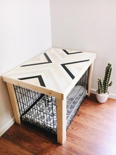 a wooden table with a metal cage underneath it and a cactus in the corner next to it