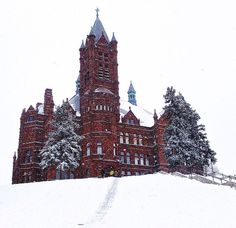 a large red building sitting on top of a snow covered hill in front of trees