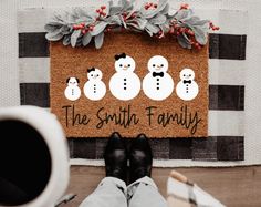 a person standing in front of a door mat with three snowmen and the words, the south family