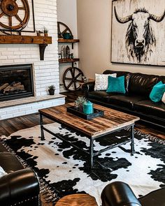 a living room with black leather couches and cow hide rugs on the floor