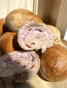 several rolls filled with meat sitting on top of a wooden table next to a window