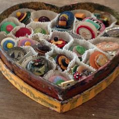 a heart shaped box filled with lots of different types of candies on top of a wooden table