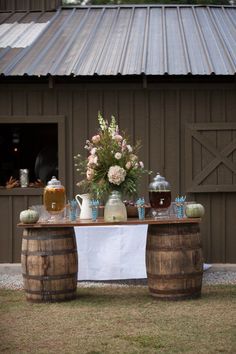 a table with vases and jars on it in front of a barn door,