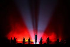 several people are standing in front of red and blue lights on stage with their backs to the camera