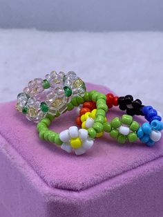 three bracelets sitting on top of a pink box covered in beads and glass beads