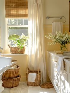 a bathroom with yellow walls and white fixtures, wicker baskets on the floor next to the bathtub