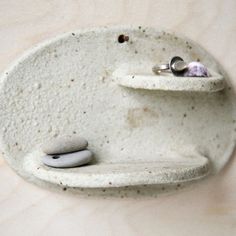 there is a small white bowl with two rocks in the bottom and a ring holder on top