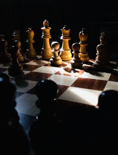 a chess board with several pieces on it in the dark, including one king and two queens