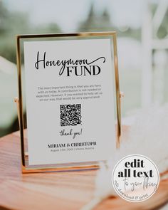 a sign that says honeymoon fund sitting on top of a wooden table next to feathers