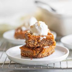 three pieces of cake sitting on top of a white plate next to a bowl of whipped cream