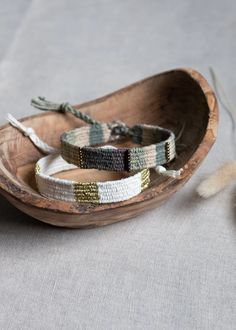 two bracelets sitting on top of a wooden boat next to a tassle