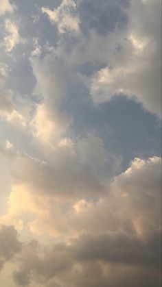 an airplane is flying high in the sky with some clouds behind it and another plane on the ground