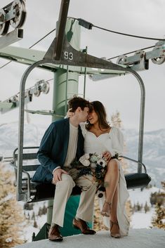 a man and woman sitting on a ski lift kissing each other in front of the camera