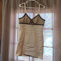 a dress hanging on a clothes hanger in front of a window with sheer curtains