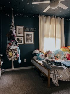 a bedroom with blue walls and lots of stuffed animals on the bed