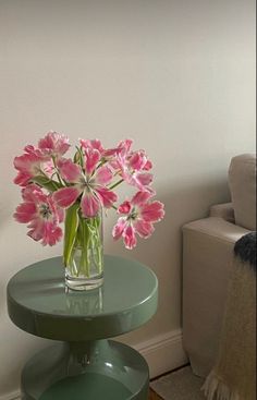 pink flowers are in a vase on a green table