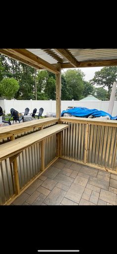 a wooden bench sitting on top of a tiled floor next to a covered patio area