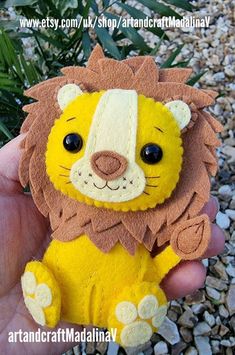 a hand holding a small stuffed animal in it's right hand, with the image of a lion on its left side