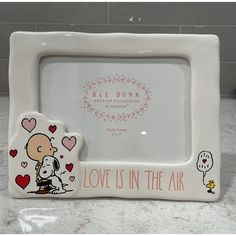 a white ceramic frame with a cartoon character on it and the words love is in the air