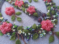 a close up of a necklace made with beads and flowers on a cloth background,