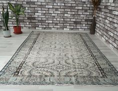 a large area rug in front of a brick wall with potted plants on the floor