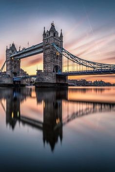 the tower bridge is reflected in the water