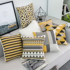 a bunch of pillows sitting on top of a couch next to a framed photo and potted plant