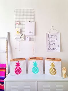 three bags with pineapples painted on them are sitting on a white cabinet in front of a wall