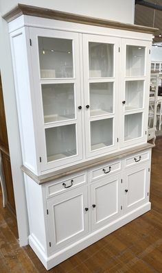 a white china cabinet with glass doors on the front and bottom, in a store