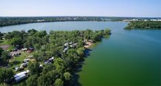 an aerial view of a lake surrounded by trees and camping trailers in the distance,