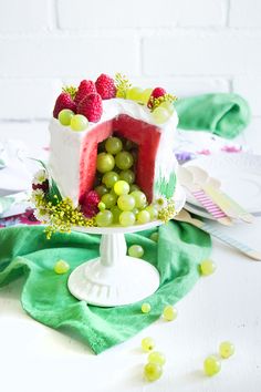 there is a cake with fruit on the top and green grapes in the bottom layer