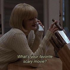 a woman sitting at a table talking on a cell phone with the caption what's your favorite scary movie?