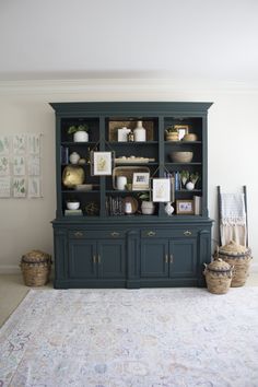 a blue china cabinet with pictures on the front and shelves above it in a living room