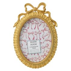 an ornate gold frame with pink ribbon on the front and bottom, hanging from a wall