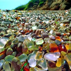 many different colored glass pieces on the ground with mountains in the background and blue sky