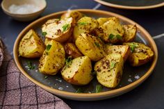 a plate full of cooked potatoes with seasoning on the side, next to a bowl of salt and pepper