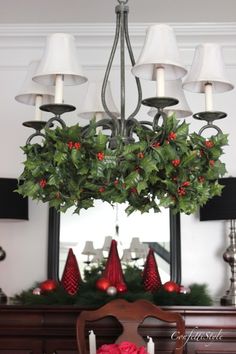 a chandelier with holly and red berries hanging from it's centerpiece