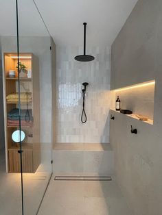 a bathroom with white walls and flooring has a glass shower door that opens up to the bathtub