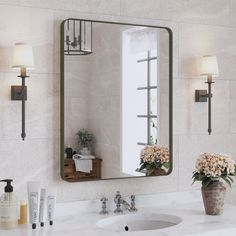 a bathroom sink with a mirror above it and flowers in the vase on the counter