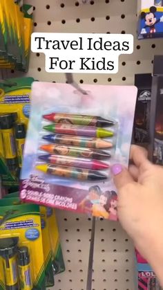 a person holding up a package of crayons in front of a store shelf