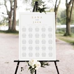 a wedding seating sign with flowers and greenery on the top is shown in front of trees