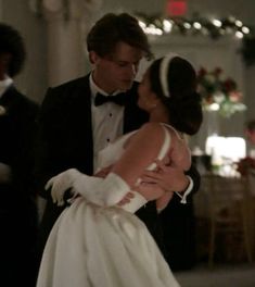 a man in a tuxedo hugging a woman in a white dress