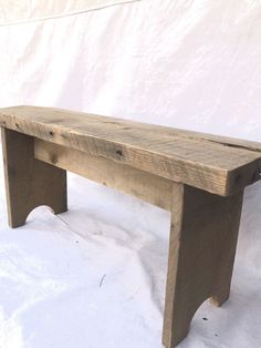 a wooden bench sitting on top of a snow covered ground next to a white wall