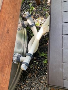 a hose connected to the side of a wooden fence next to a building with shingles on it