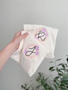 someone is holding two personalized towels with the letter k on them and one has a flower in it