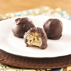 three chocolate covered desserts on a white plate with a gold and blue place mat