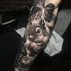 a man's arm with a squirrel and leaves on it